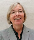 Laura Doughty, Director of Income Generation and Communications, in a grey check jacket and glasses, laughing