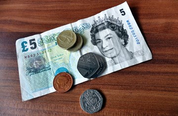 UK currency British five pound note and assorted coins