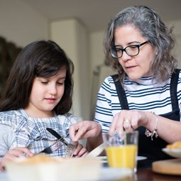 older woman helping child cut up dinner