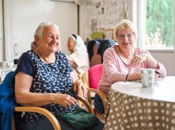 Two women sitting by a table in a residential care home