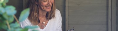 Carer Jane smiling and looking at phone in her garden
