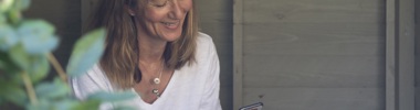 Carer Jane smiling and looking at phone in her garden