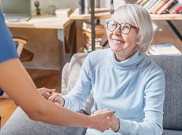 smiling older woman with glasses looking at paid care worker