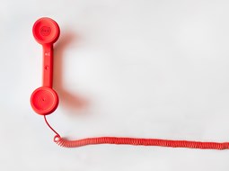 red corded telephone on a pale background