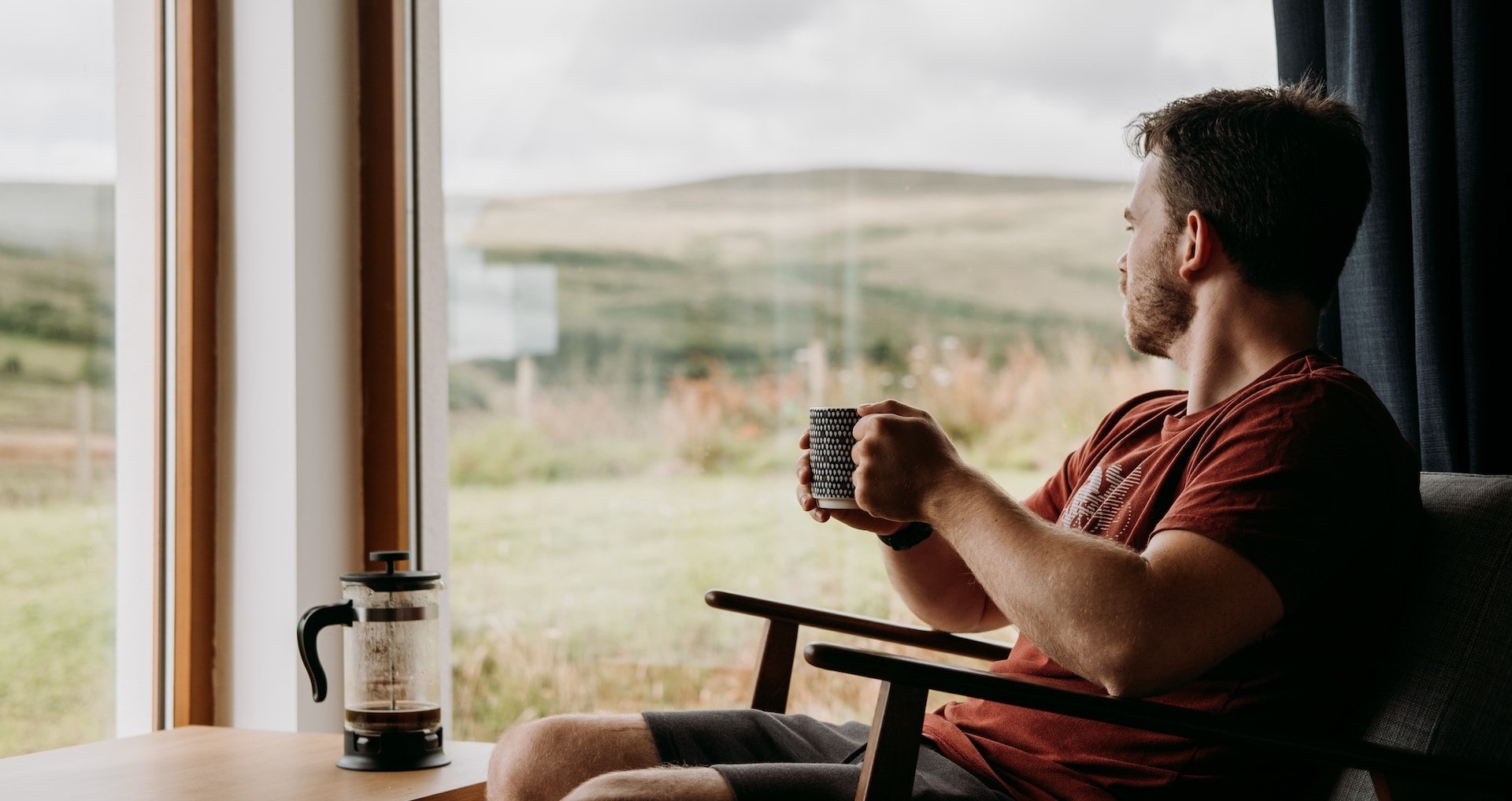 man with cup of coffee staring out the window