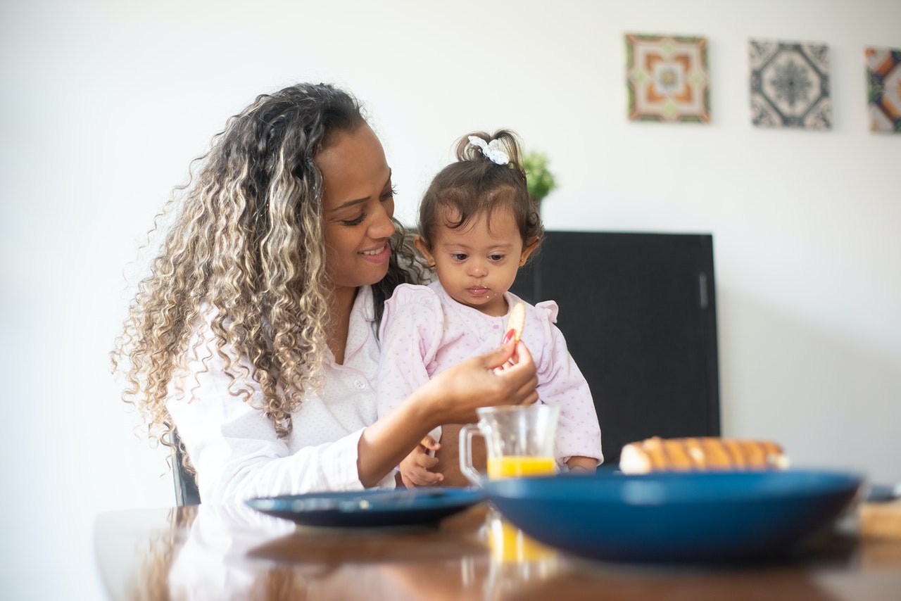 Woman eating lunch with young child with Down's syndrome