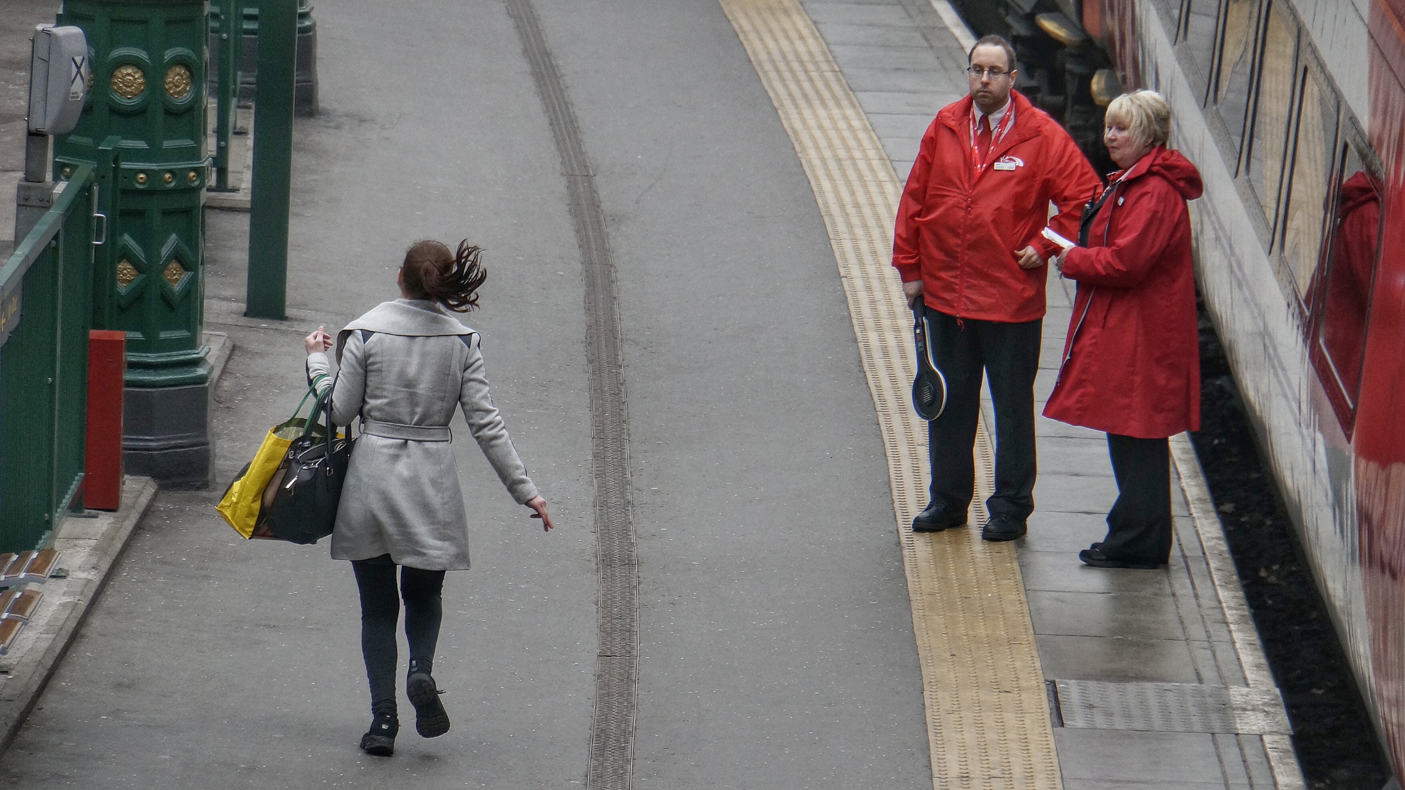 woman on a station platform running for a train