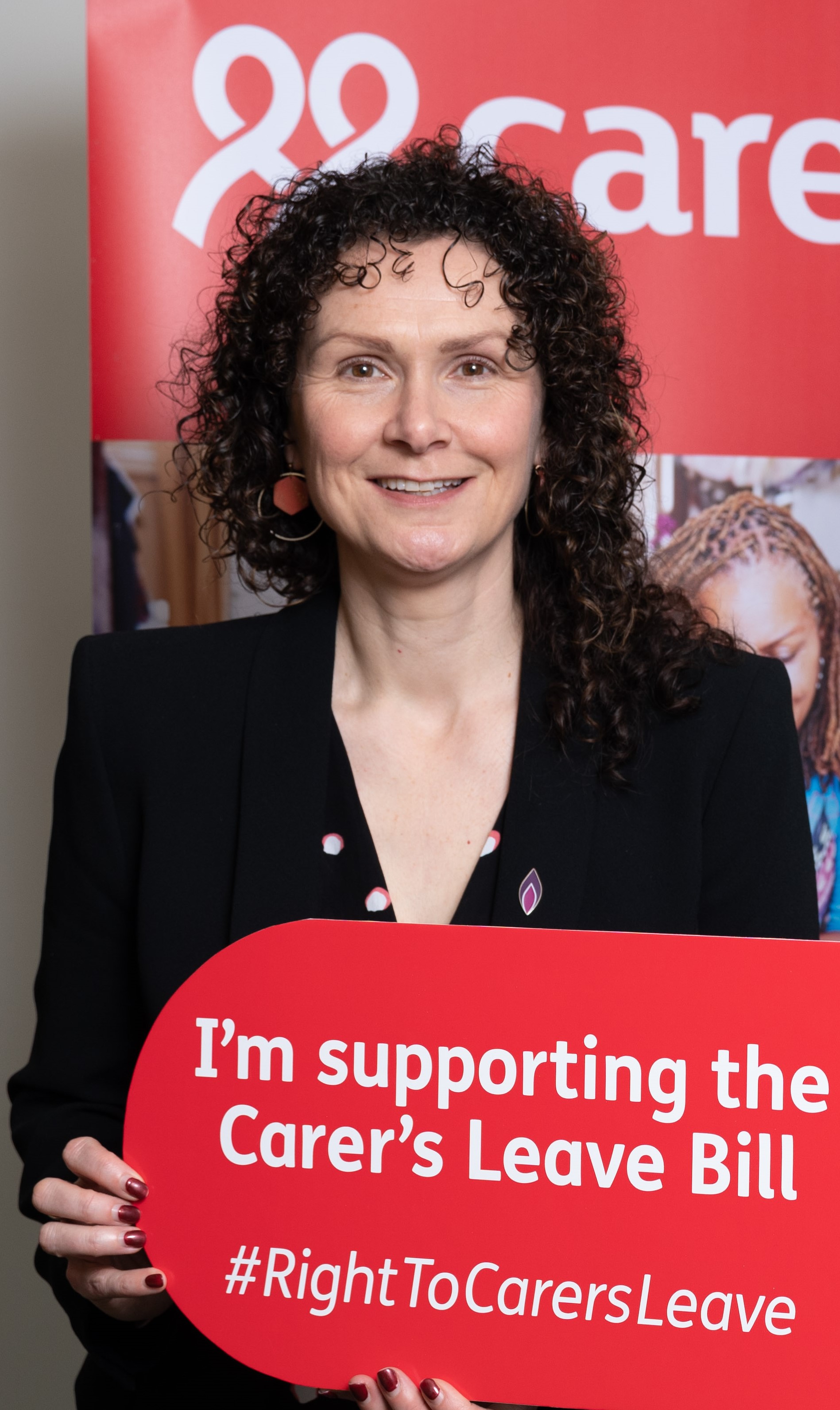 Wendy Chamberlain MP holding up Right to Carers Leave sign