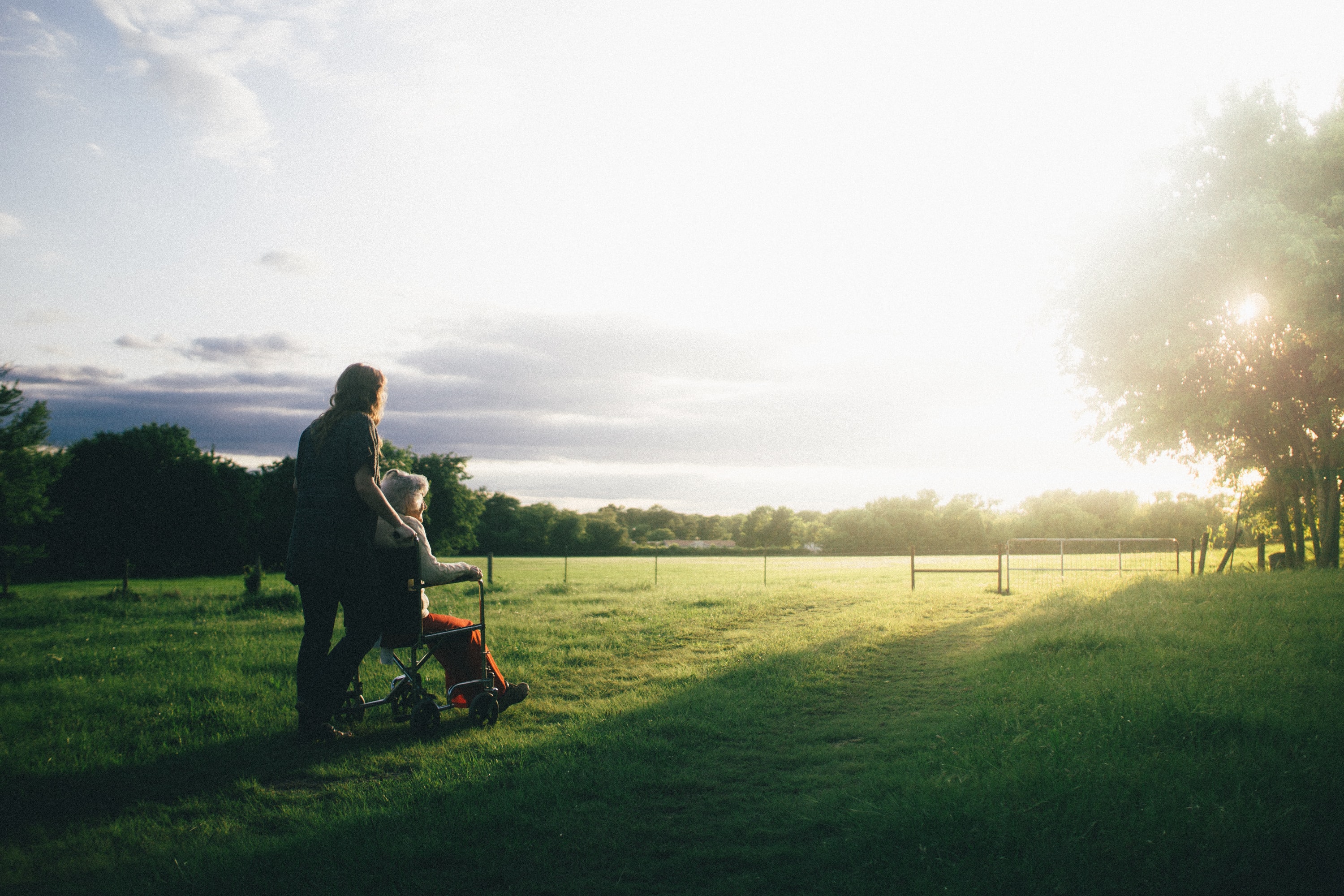 woman pushing person in wheelchair across a field