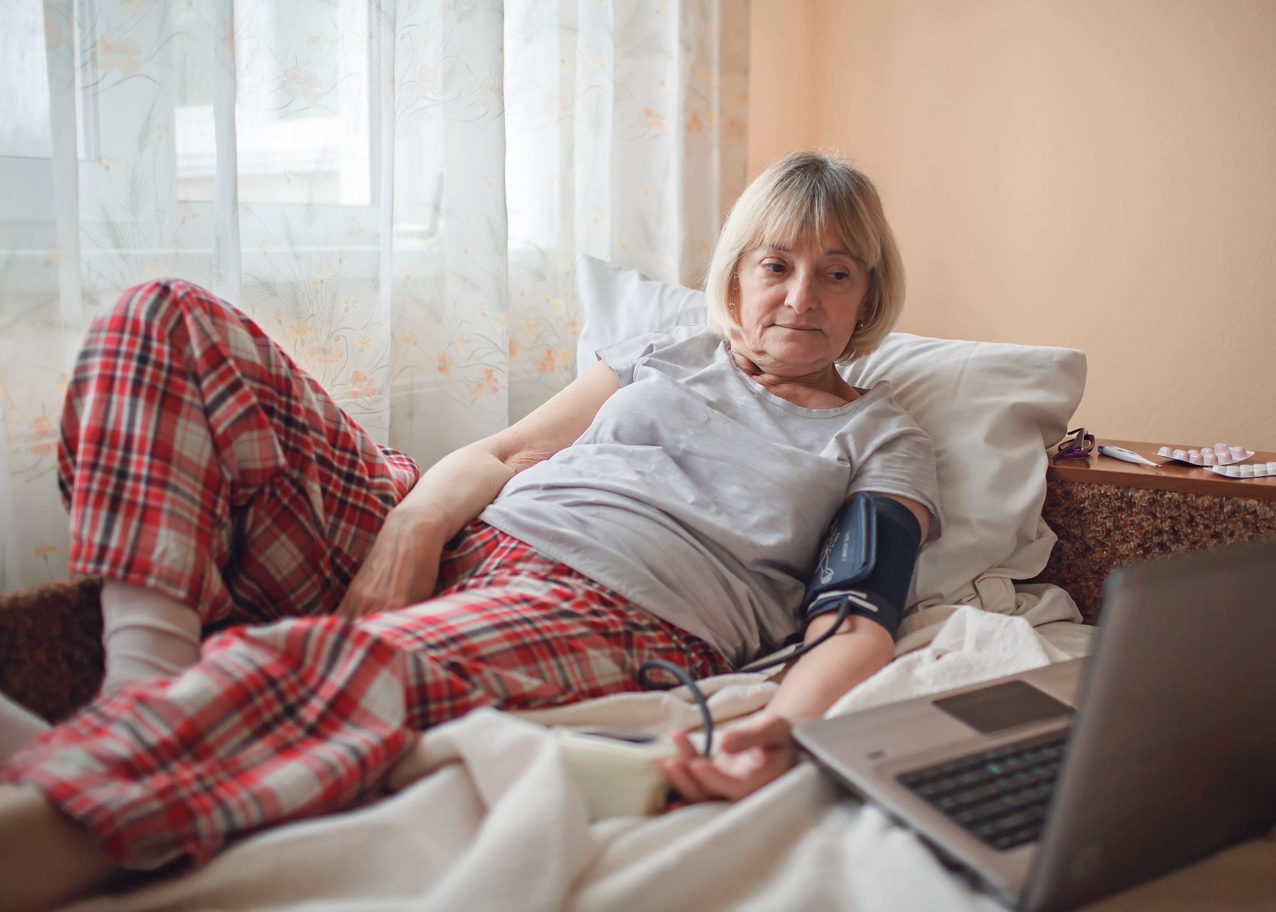 woman with blood pressure monitor using a laptop