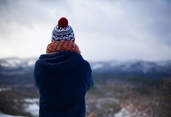 Woman wearing bobble hat looking out towards landscape