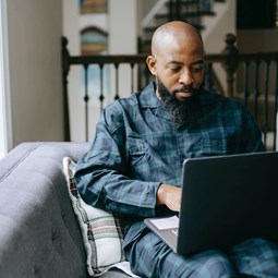 man in bedroom using a laptop