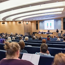 Rows of AGM attendees listening to people talking on stage