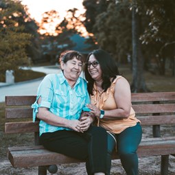 two people on a bench talking outdoors in summer